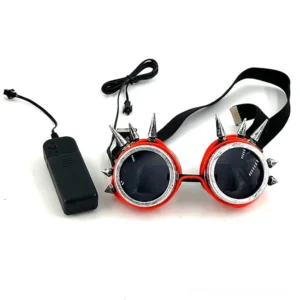 Steampunk goggles with red frame and silver metal spikes shown with battery power controller on white studio background