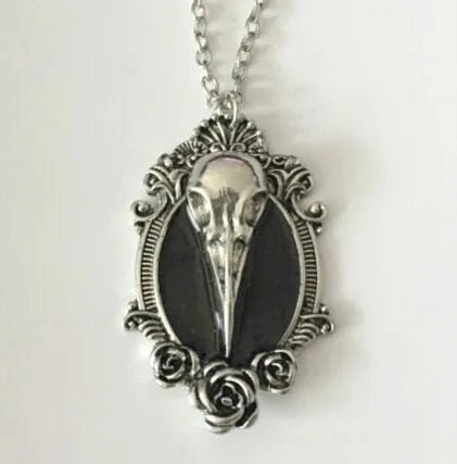 Antique silver finish Gothic bird skull necklace featuring black enamel inlay and Victorian filigree scroll decoration on pure white background - steampunk pendant close-up