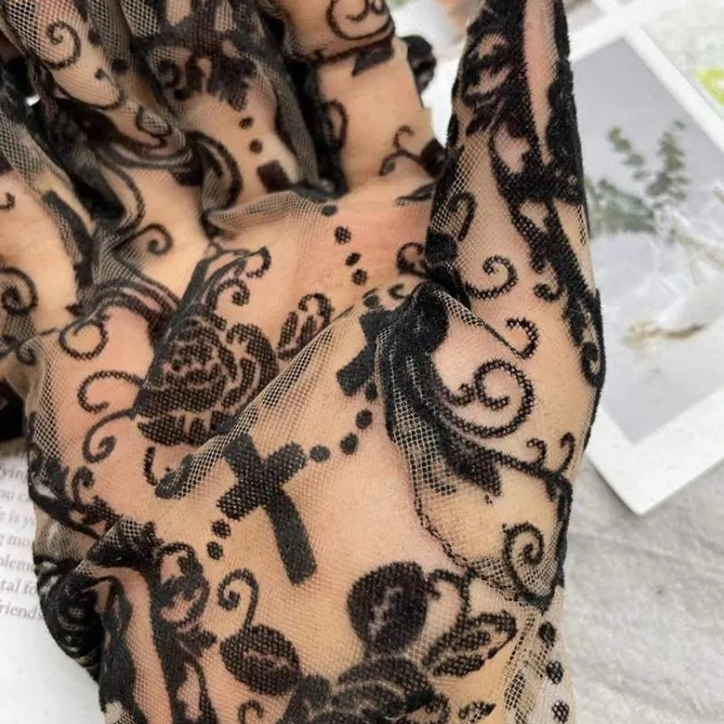 Close-up detail of gothic steampunk glove showing black swirl, rose and cross flocked design on nude sheer mesh fabric with ornate pattern definition
