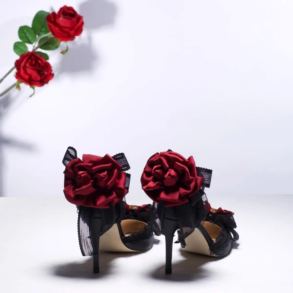 Rear view of steampunk gothic lolita heel featuring large wine-red satin roses on heel counters, black lace upper, and ornate ankle strap buckle - back perspective