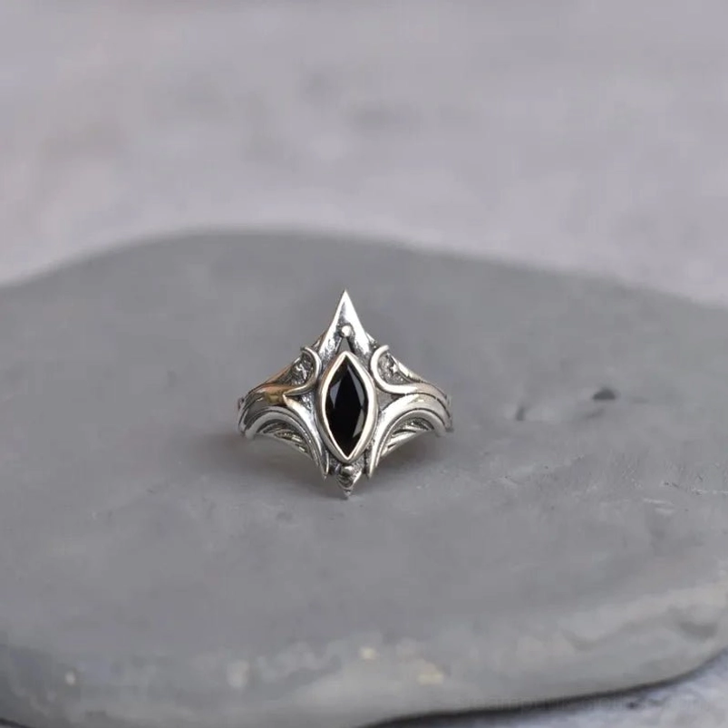 Gothic steampunk silver ring flat lay front view displaying ornate scroll engravings, polished silver metal finish, and black onyx center stone