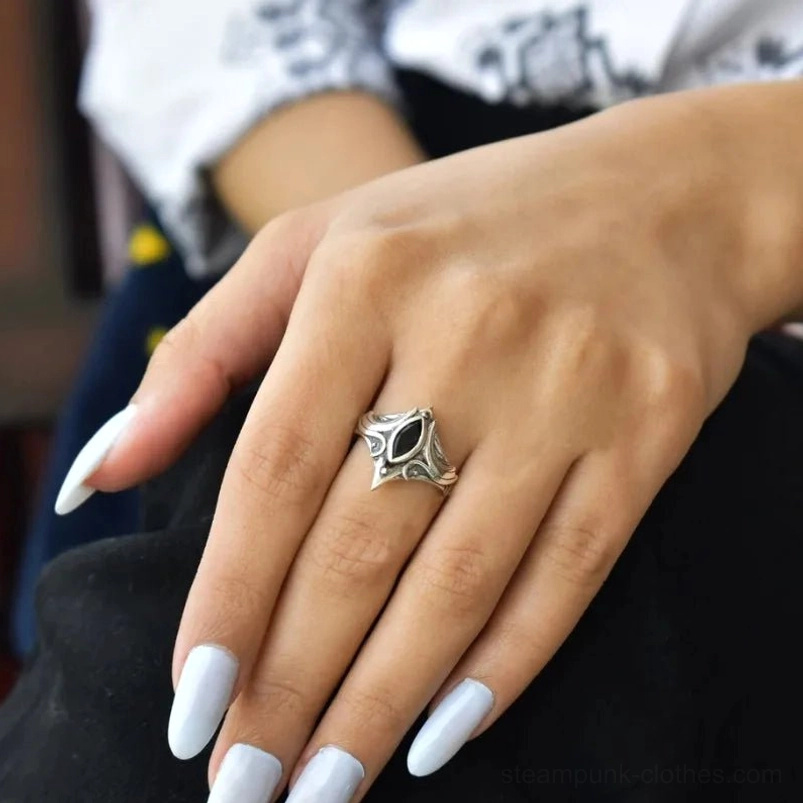 Steampunk gothic onyx ring worn on middle finger showing matching carved silver gothic design with elegant hand pose and light nail polish