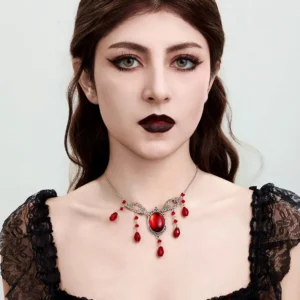 Frontal portrait of gothic steampunk vampire choker necklace worn by model in black lace puff-sleeve dress, displaying intricate filigree design and crimson gemstone accents in minimalist studio setting