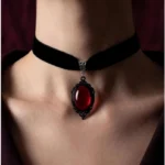 Black velvet choker necklace with red cabochon pendant and vintage filigree metal frame, front close-up view on model