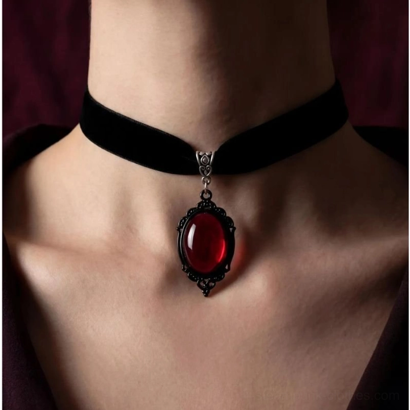 Black velvet choker necklace with red cabochon pendant and vintage filigree metal frame, front close-up view on model