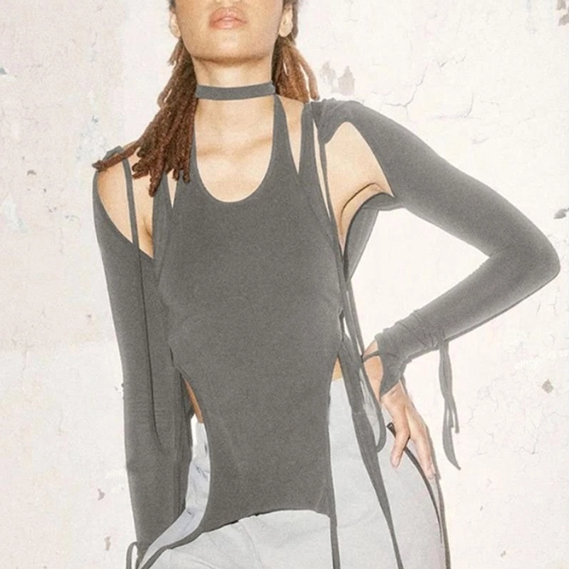 Steampunk halter top with detached sleeve shawl component in charcoal grey knit, styled with choker accessory and bare shoulder cutouts, half-body front view against textured white wall