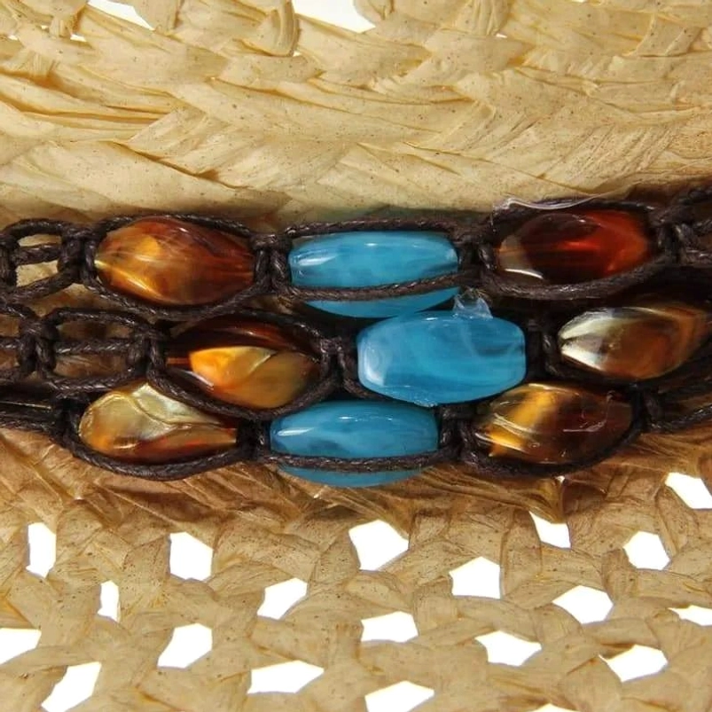 Close-up detail of steampunk hat band showing turquoise gemstone cabochons, amber beads, woven straw texture and bronze-tone metal accents