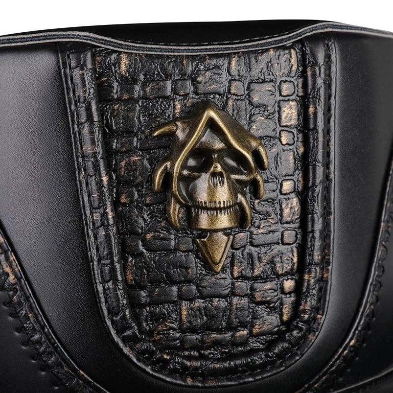 Close-up detail of steampunk hat emblem featuring aged bronze skull ornament on crocodile-patterned leather