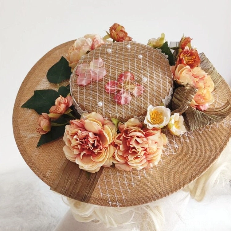 Wide-brimmed Victorian steampunk hat overhead view displaying burlap brim, pink fishnet veil pattern, artificial flowers with green leaves on white fur studio surface