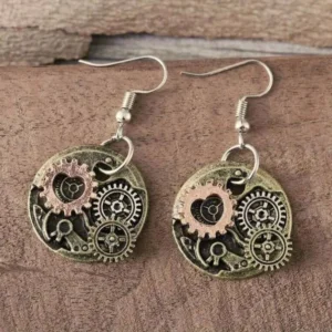 Rose-gold tone steampunk heart gear earrings displayed on brown wooden surface, showing hollow heart and rotating gear mechanical design