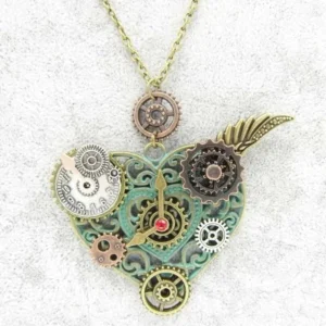 Steampunk heart pendant necklace featuring clock face embellishments, mixed metal tones, red jewel center, and wing accent shown in flat lay top front view