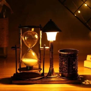 Steampunk hourglass desk lamp with LED glow and pen holder on wooden desk, showing warm golden light and bronze finish
