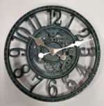 Steampunk industrial wall clock with verdigris patina, hollowed Arabic numerals, exposed gear movement, and metallic hands on white background