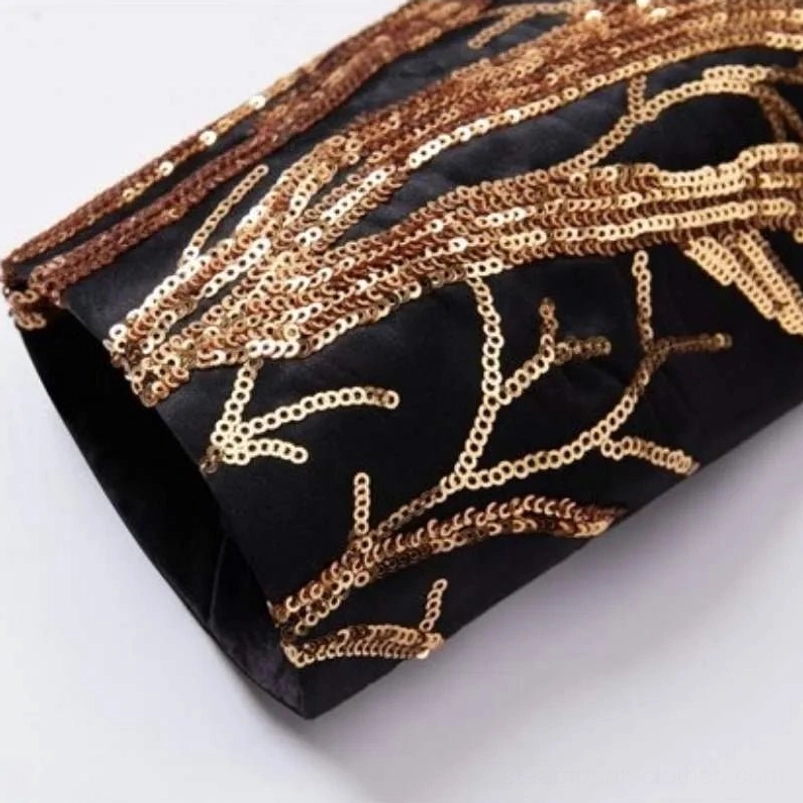 Flat lay detail of gold sequin embroidery on black sleeve with glossy sequin texture
