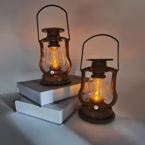 Two retro LED kerosene lanterns displayed together with bronze metal frames on vintage hardcover book collection desktop