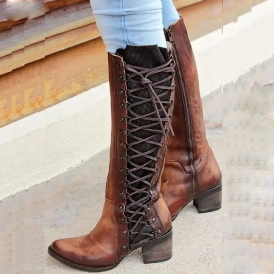 Distressed brown leather steampunk knee-high boots with metal eyelet side lacing, full-length side zipper, and block heel, worn on model showcasing authentic vintage character and adjustable fit system
