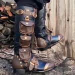 Steampunk knee-high cosplay boots with black and brown leather, metal studs, decorative buckles and utility pouches - outdoor side view showcasing industrial Victorian design details