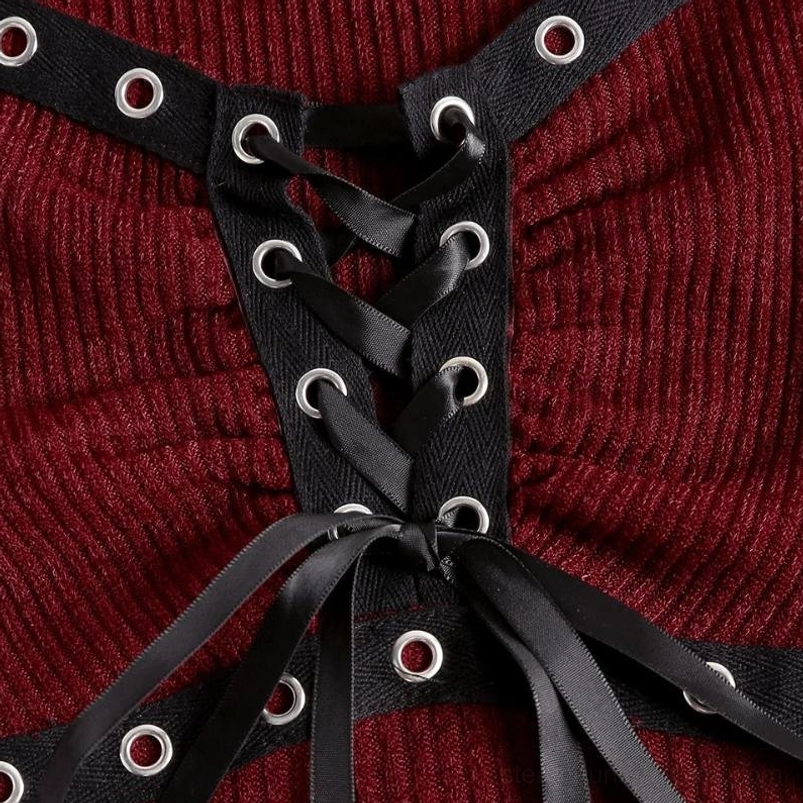 Close-up macro detail of steampunk knit top showing black satin lace-up, metal eyelet grommets, and ruched ribbed burgundy knit fabric texture