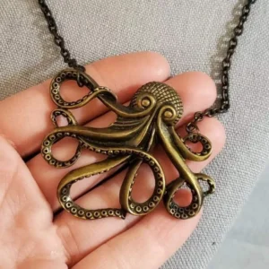 Antique bronze octopus pendant necklace close-up showing engraved tentacle details and suction cup engravings held in hand