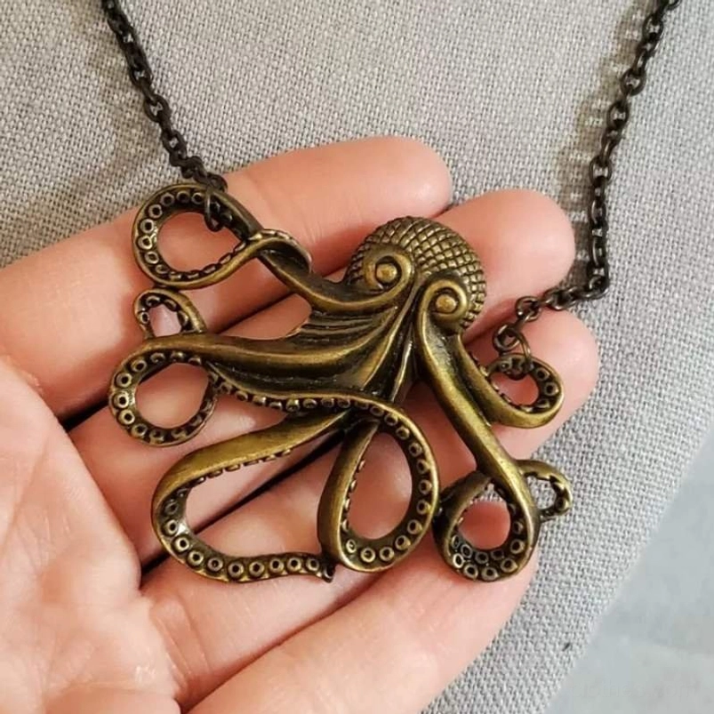 Antique bronze octopus pendant necklace close-up showing engraved tentacle details and suction cup engravings held in hand