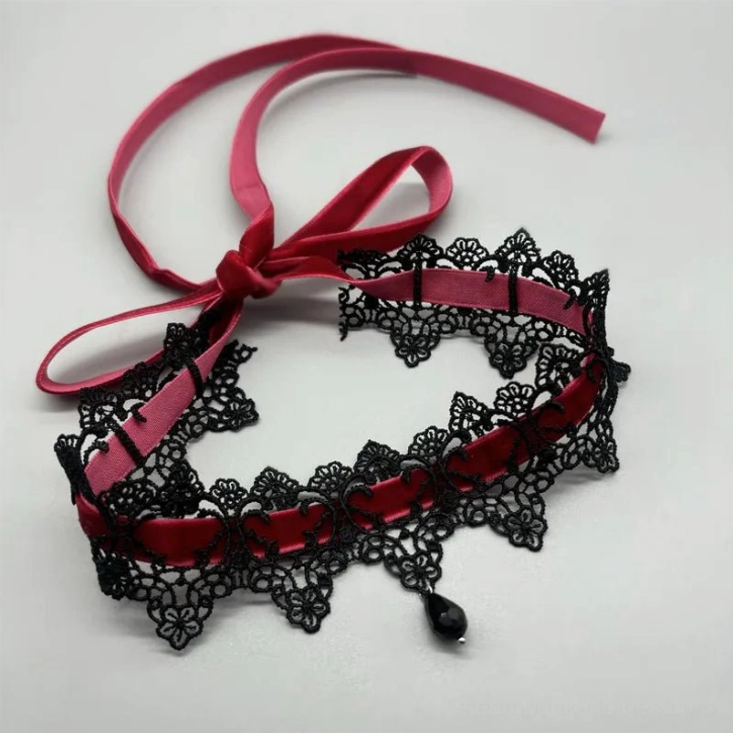 Steampunk choker necklace side angle flat lay, black lace ribbon design with burgundy velvet and teardrop pendant accessory