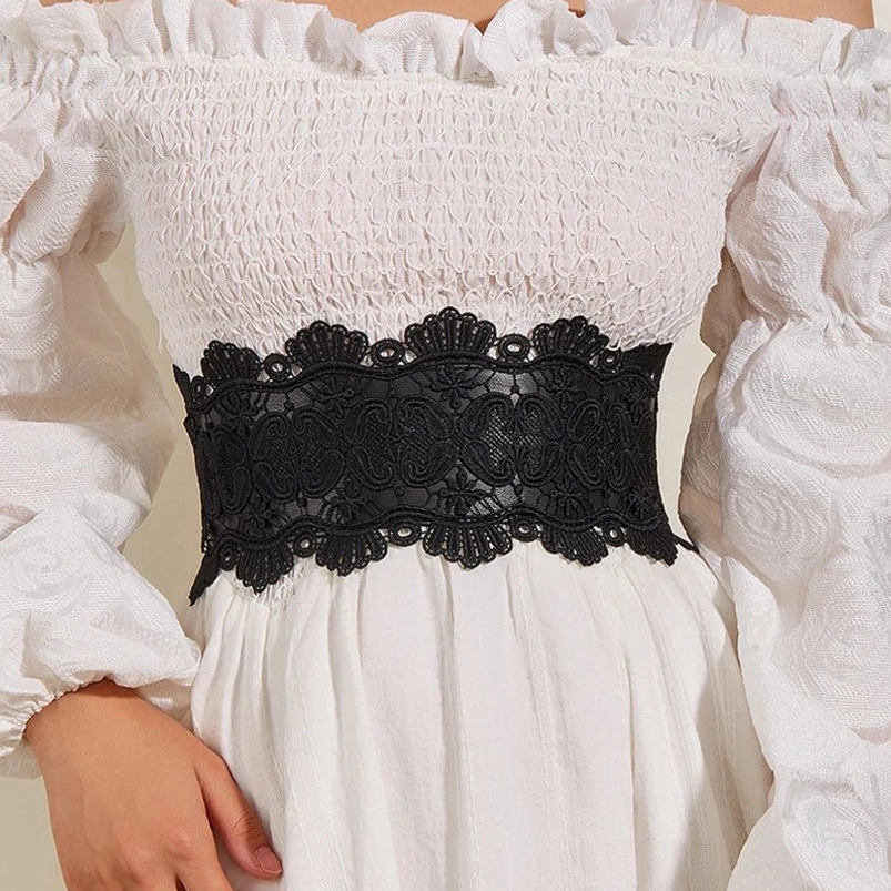 Black steampunk elastic lace corset belt worn on female model with off-shoulder white ruffled dress, front view showcasing waist definition and Victorian aesthetic