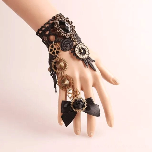 Steampunk lace wrist cuff on mannequin hand, 3/4 view showing black mesh lace, bronze hardware, bow ring, and large black gem inlay