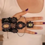 Black lace steampunk slave bracelet with bronze cameo and chain ring detail, overhead view on model with purple nail polish