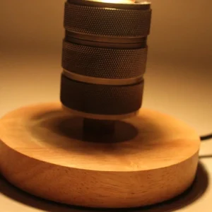 Steampunk lamp partial assembly showing stacked knurled metal components and warm glowing Edison bulb on wooden base close-up detail