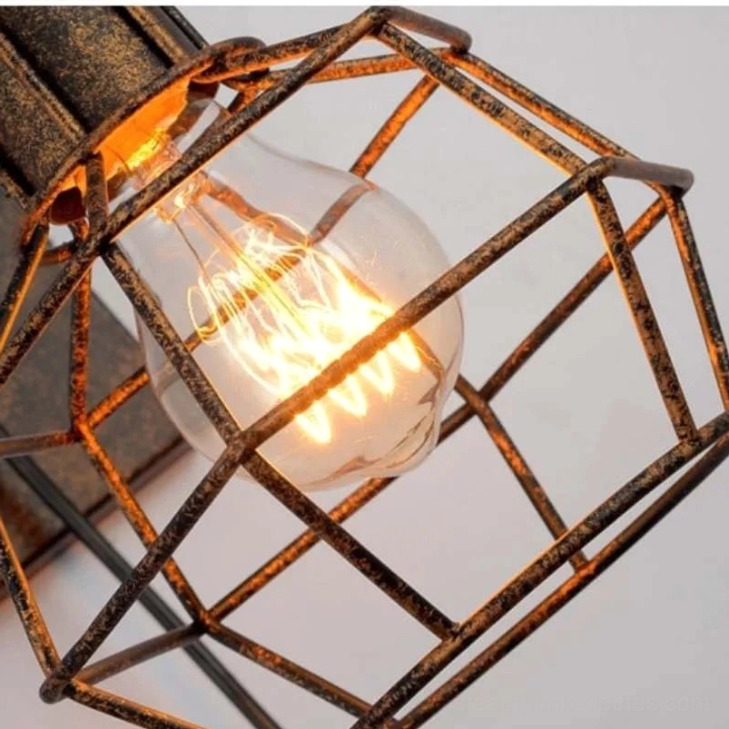 Close-up macro photograph of steampunk lamp cage detail showing rusty bronze wire frame, polygonal cage structure, and vintage Edison bulb socket configuration