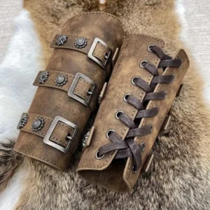 Matched pair of distressed brown leather steampunk arm bracers displayed on animal fur, featuring vintage metal studs, ornate buckle straps, and embossed flower ornaments showcasing authentic medieval bracer design and craftsmanship