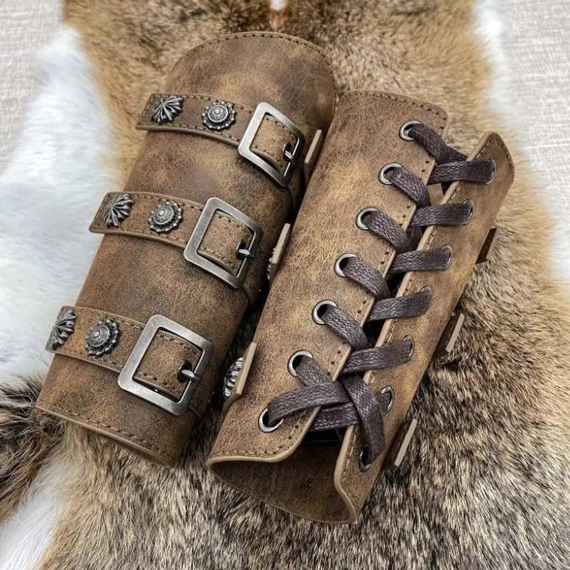 Matched pair of distressed brown leather steampunk arm bracers displayed on animal fur, featuring vintage metal studs, ornate buckle straps, and embossed flower ornaments showcasing authentic medieval bracer design and craftsmanship