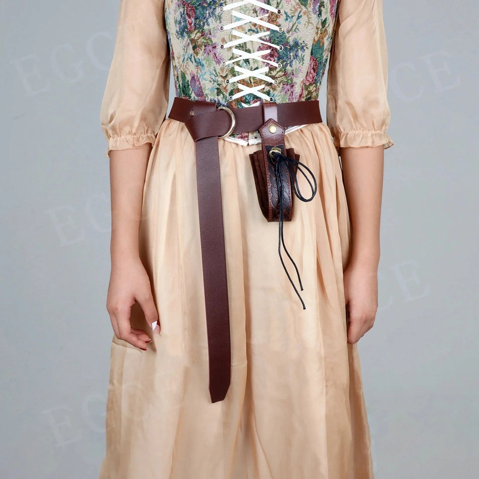 Steampunk leather waist belt worn by female model in vintage corset, front view displaying adjustable metal buckle system and functional Celtic knot pouch with black leather drawstrings and secure snap closure