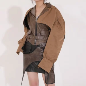 Steampunk leather jacket side profile showing asymmetrical design, contrast color blocking, cinched waist with belt detail, and cropped silhouette on model