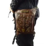 Steampunk leather leg holster bag rear left view on male model, showcasing embossed leather surface, brass rivets, and vintage hardware details