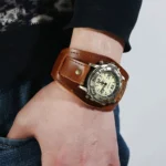 Brown steampunk leather watch with bronze bezel on wrist, showing side view of distressed cowhide strap and cream dial with bold hour markers