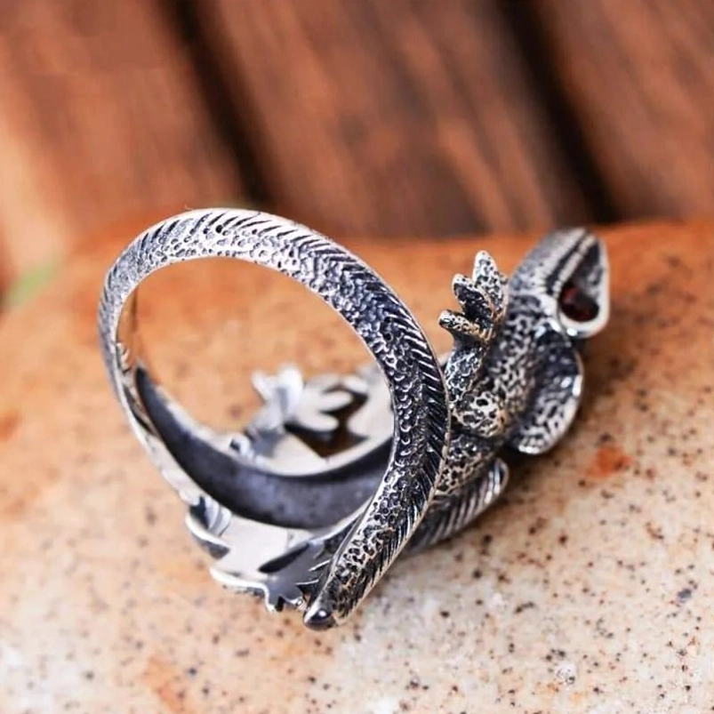 Wrap-around silver lizard steampunk ring overhead view showing reptile scale patterns, vintage finish, and glowing red gemstone eye
