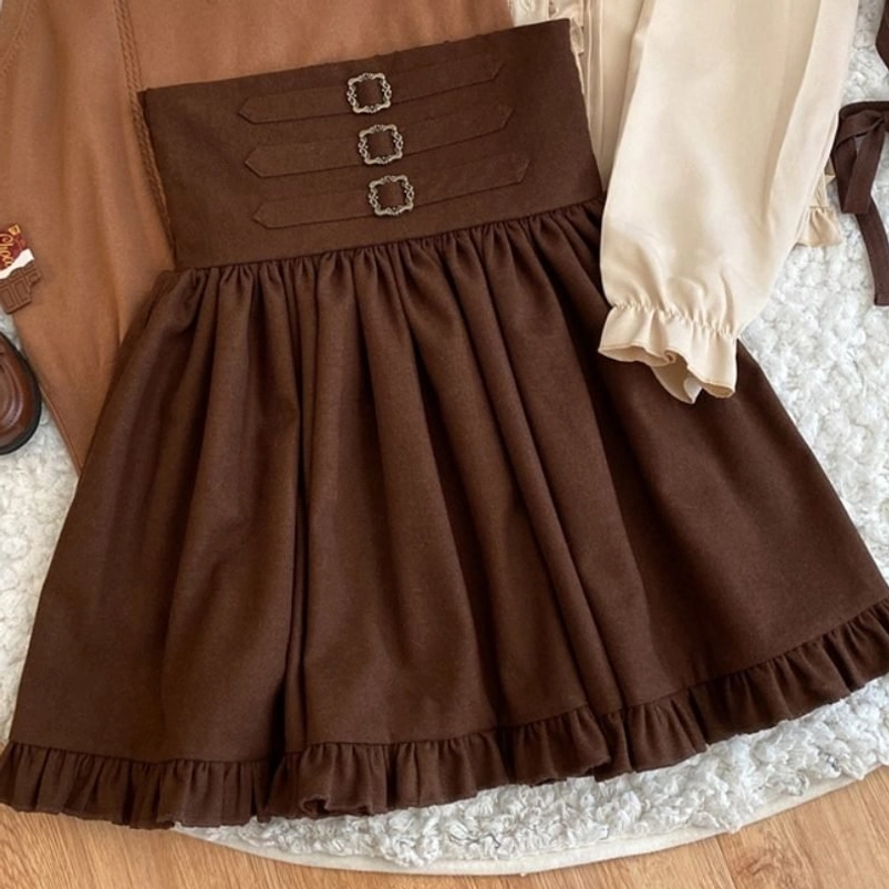 Steampunk lolita skirt flat lay on wooden table with beige ruffled blouse showing waistband detail and pleated skirt construction