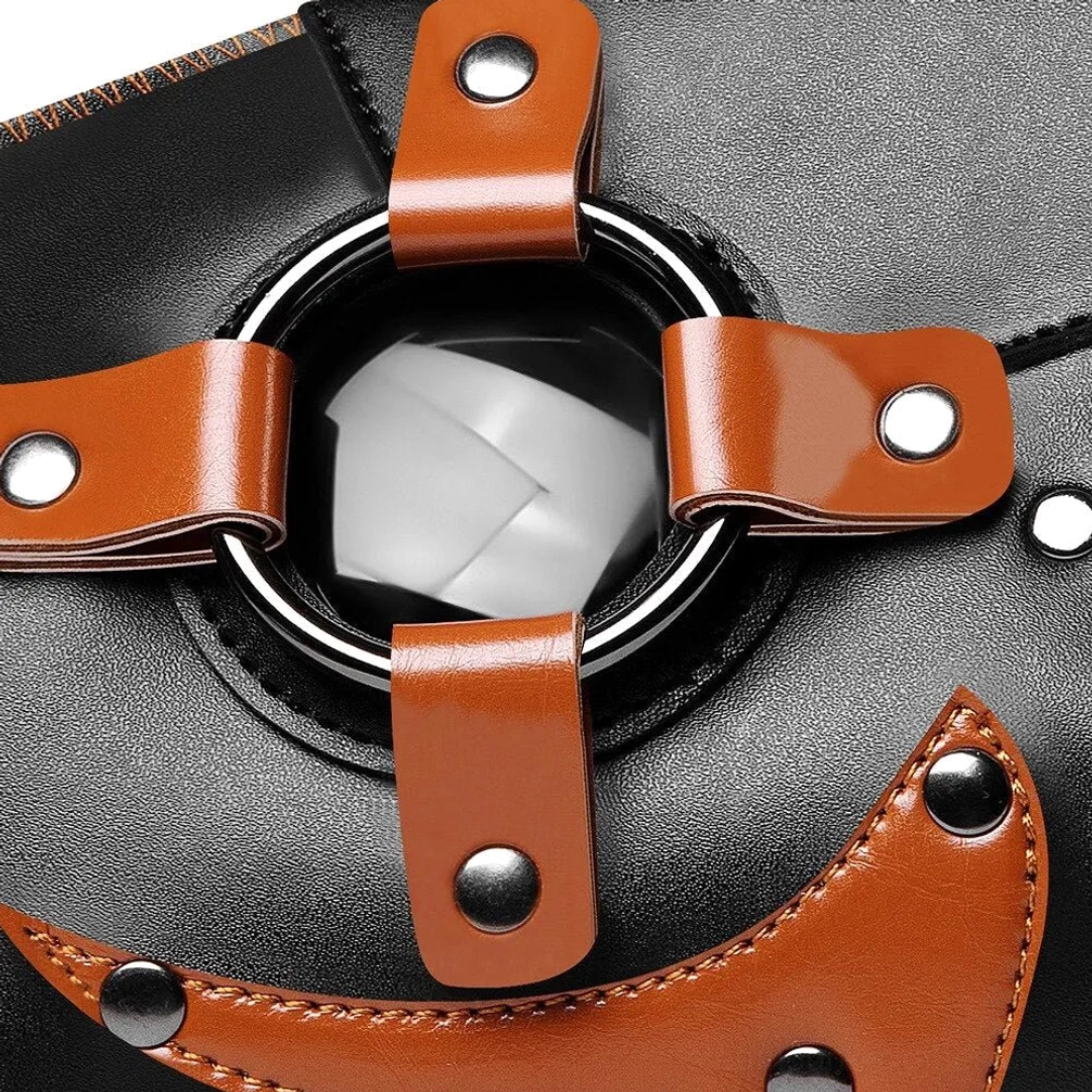 Close-up top view of steampunk mask front showing clear round polycarbonate lens, brown leather harness straps, and silver metal rivets with detailed stitching