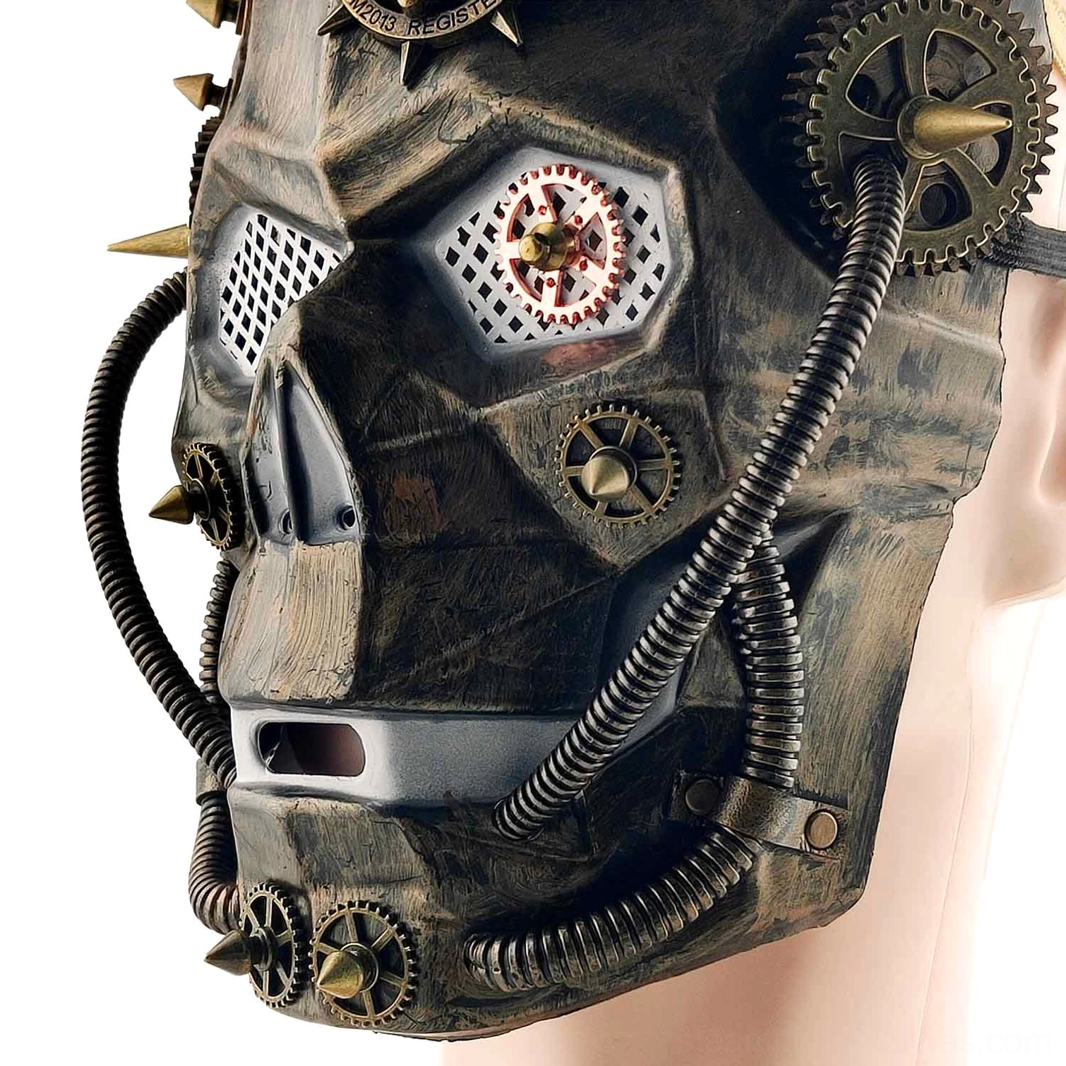 Right side profile view of steampunk skull mask on mannequin head, displaying bronze metal coating, side-mounted gears, flexible rubber tubing, and spike details