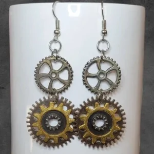 Vintage steampunk gear dangle earrings displayed on stand showing aged mixed metal tones and stacked mechanical pendant details