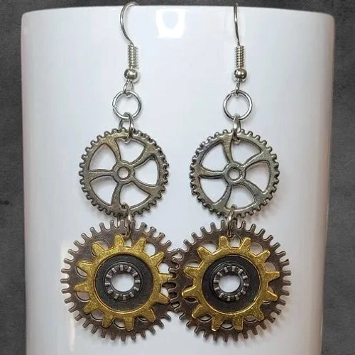 Vintage steampunk gear dangle earrings displayed on stand showing aged mixed metal tones and stacked mechanical pendant details