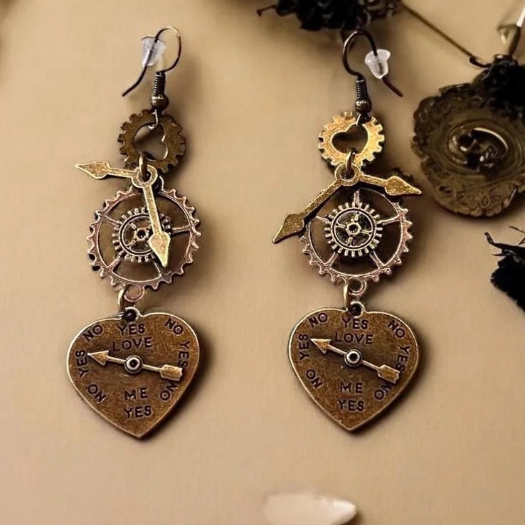Steampunk heart earrings with bronze gears and arrow details on tabletop display