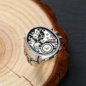 Steampunk mechanical gear ring top view displaying intricate exposed watch movement design and carved ring shank details with wood texture background