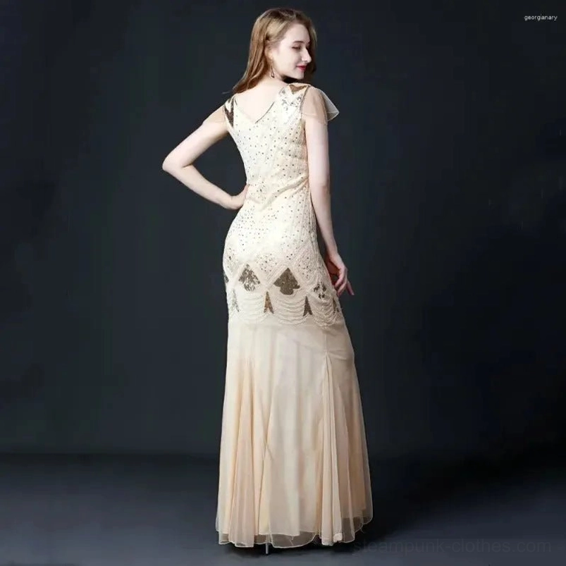Open back design of steampunk evening gown showing detailed sequin patterning across lower back, sheer mesh skirt, and floor-length silhouette - rear three-quarter view