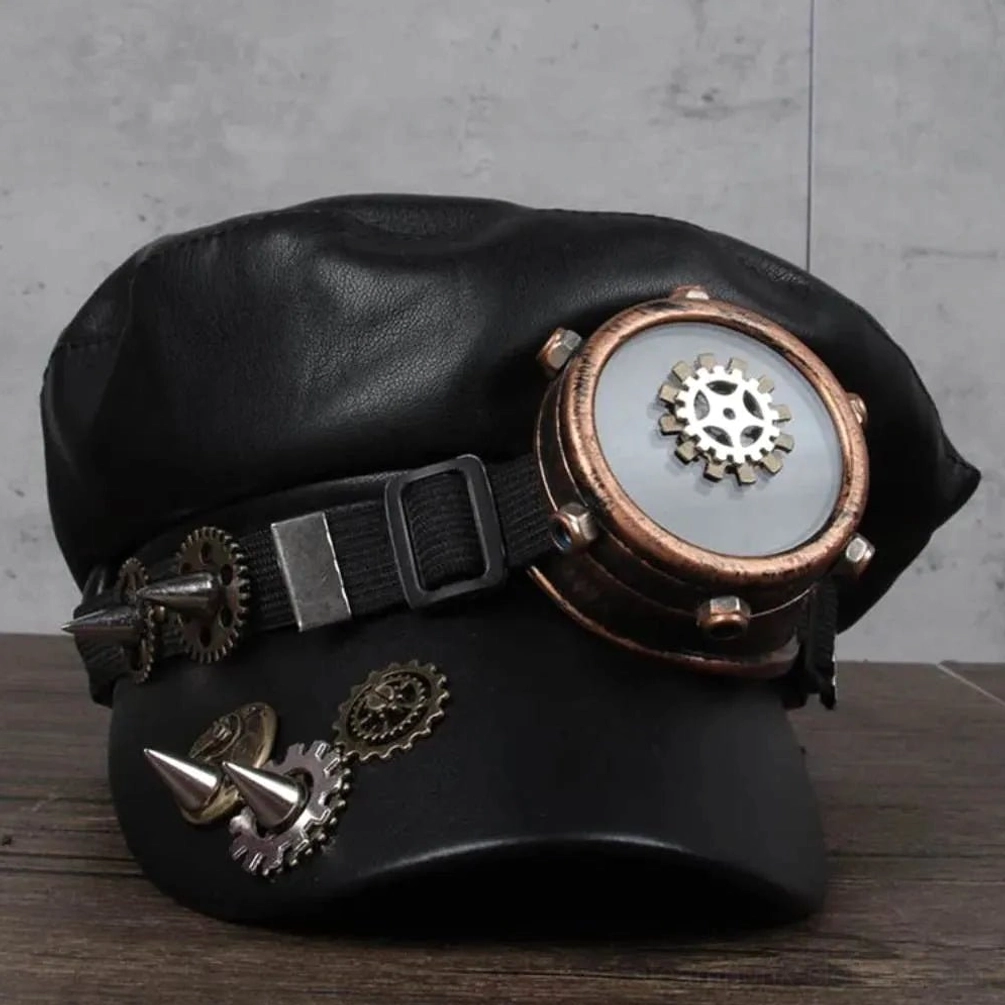 Steampunk military cap front three-quarter view showing black faux leather construction, integrated bronze aviator goggles, brass gear ornaments, and spike accents on structured crown