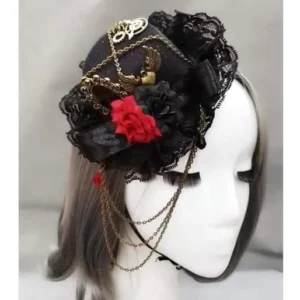 Steampunk gothic mini top hat front three-quarter view featuring black lace ruffle, red fabric rose, hanging face chains, and bronze gear decorations on mannequin