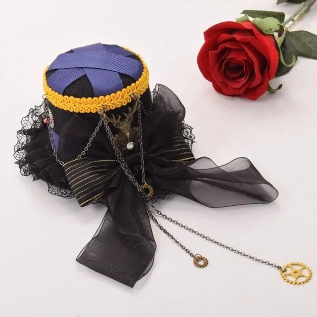 Three-quarter overhead angle of steampunk mini top hat featuring sheer black bow with striped ribbon and decorative deer charm pendant against white background with red rose