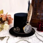 Steampunk mini top hat with compass and feather decoration displayed in overhead three-quarter view on vintage wooden surface with floral backdrop