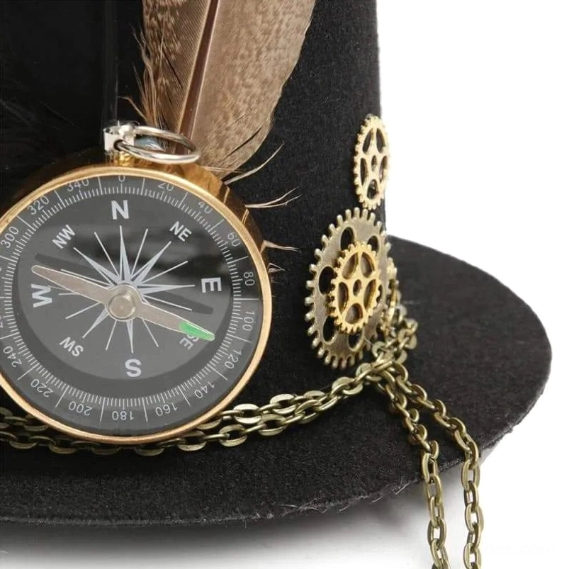 Close-up detail of steampunk mini top hat showing brass gears, compass decoration, feather plume and extended metal chain